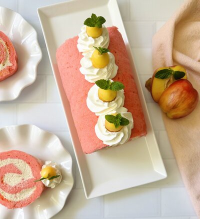 a pink swiss roll cake decorated with whipped cream and lemons