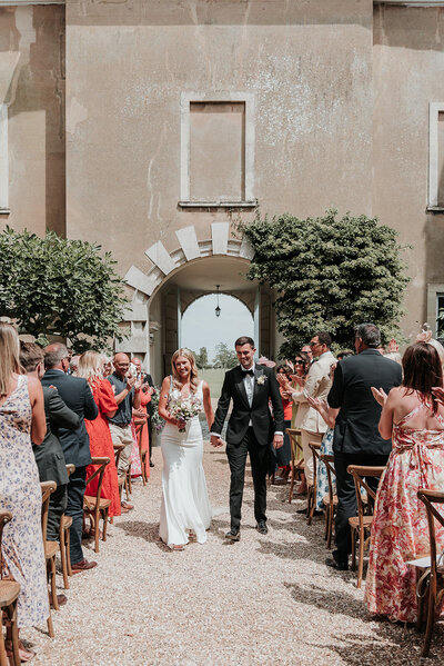 Bride and Groom celebrate down aisle after the outdoor ceremony at Firle Place, East Sussex