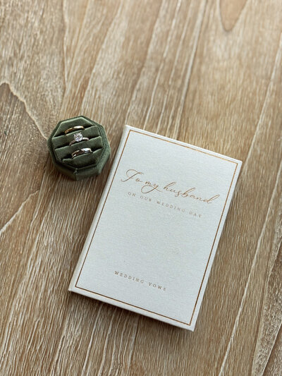 Wedding invitation with a green ring box with rings on a wooden background