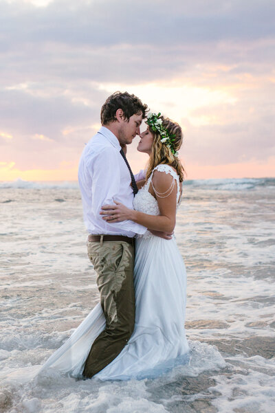 Bride and groom embracing in ocean waves at sunset at Sodwana Bay, photographed by a Bendigo wedding and portrait photographer. 