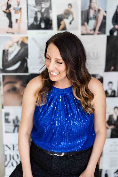 Brand strategist in sparkling royal blue halter top sharing authentic smile against black and white photography wall