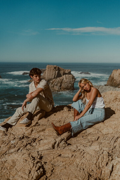 editorial style couples photo with attractive young couple sitting on the rocks in Big Sur California
