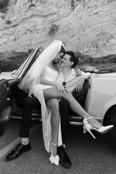 bride in groom in classic white car next to mountain side
