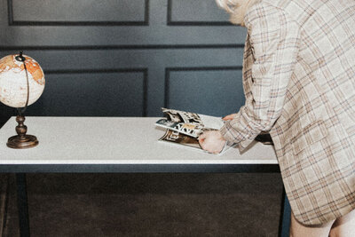 A woman is bent over reading a magazine on a table.