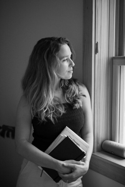 Black and white image of a practitioner at Alyn Wellness Studio holding a stack of books