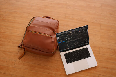 Open laptop and leather bag on floor