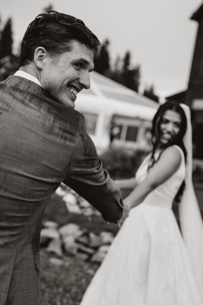 Groom smiles at bride while holding her hand during rainy wedding at Breckenridge venue.