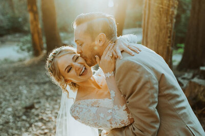 Wedding couple holding each other laughing under the trees and sun