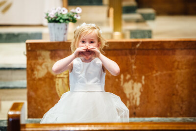 Flower girl holding up heart sign with her hands