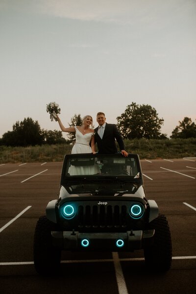 Bruidspaar staat in een Jeep