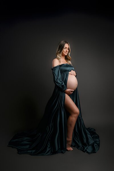 Pregnant mom in teal gown on gray background in studio