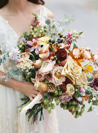 Lush, untamed bridal bouquet with garden roses, wildflowers, hops, blackberries, fruiting branches, ranunculus, copper beech, and natural greenery. Early fall RT Lodge wedding floral design by Rosemary & Finch, Nashville based florist.