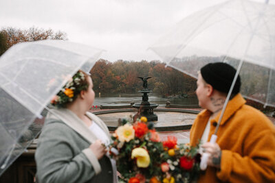 fall central park elopement couple looking at bethesda terrace with umbrellas