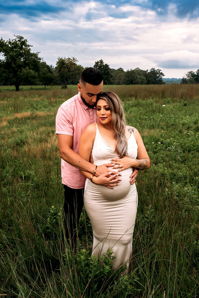 Intimate couples maternity portrait in open field with dramatic sky