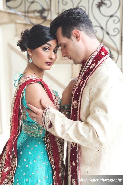 Bride and groom embrace in traditional Indian clothing.