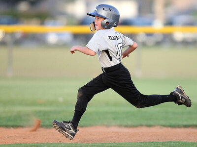 Young Boy runs the bases after hitting a run at this baseball game