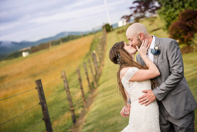 Bride and groom embracing and kissing in an open field at Taylor Made Farms by Charlotte wedding photographers DeLong Photography
