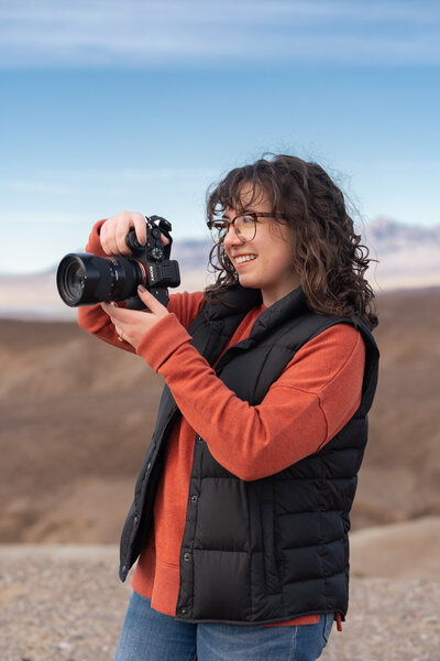 A photographer holding a camera up to their face