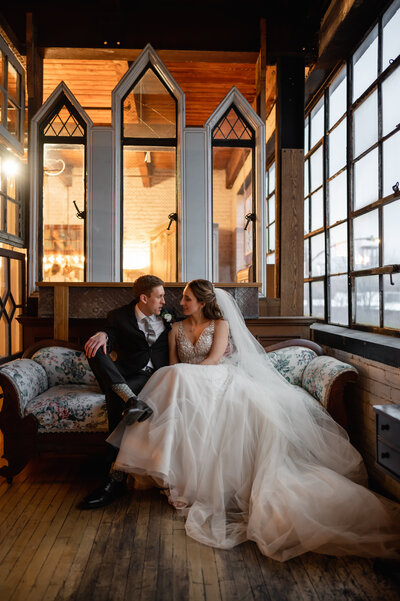 Bride and groom sit on a vintage couch at Salvage One