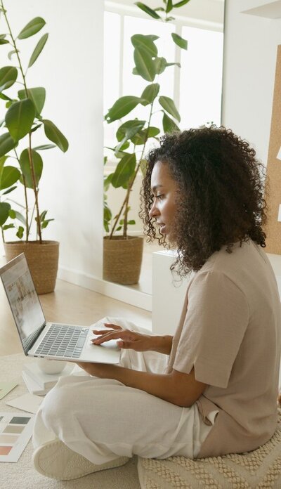 Young woman working on laptop near potted plant