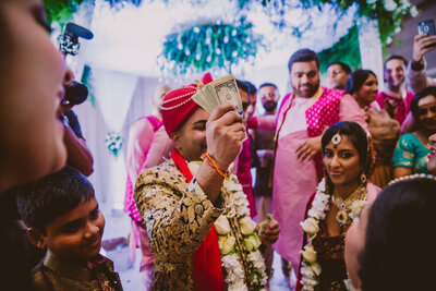 Groom showing off money during the jhutha chupai at the hindu wedding in queens museum in nyc