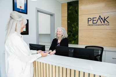 Prosthodontist warmly welcoming a patient at Peak Prosthodontics in Lethbridge, Alberta, for full mouth rehabilitation consultation.
