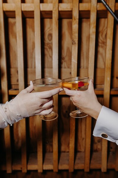 two brides clink two cocktails and cheers