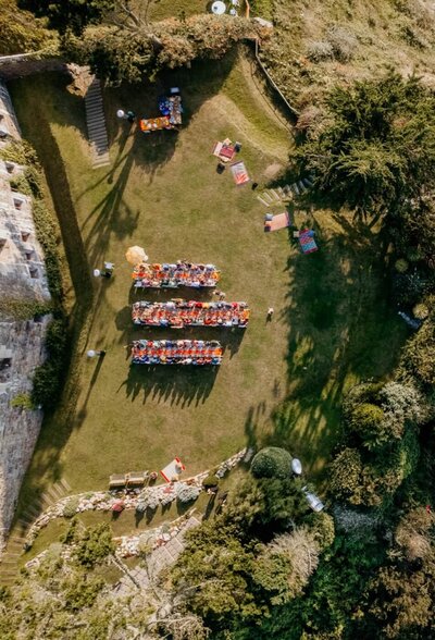 An aerial view of one of the lawns with three long tables set up for a reception dinner