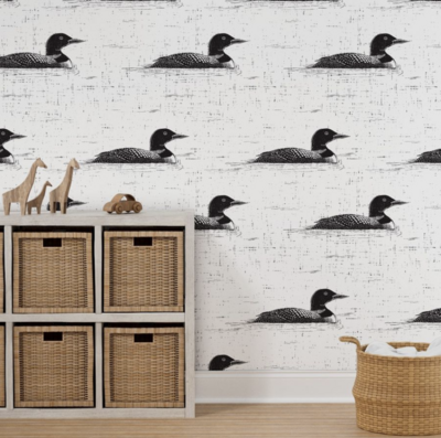 Hand drawn, highly textured black and white loons swim on smooth water on this large scale wallpaper that covers the walls of a child's boho nursery.