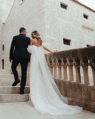 bride and groom holding each other walking up stairs