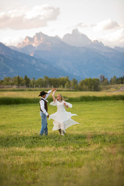 A bride and groom on the shores of Jackson Lake during their Grand Teton elopement, with the Teton mountains and the glowing sunset creating a breathtaking backdrop.