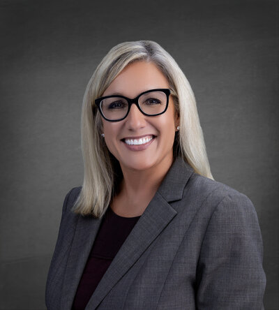 headshot of a woman in a gray blazer smiling