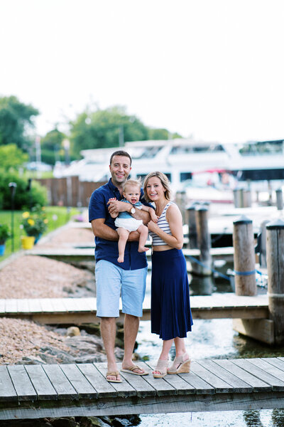 family standing on the  dock smiling into the camera on Lake Minnetonka