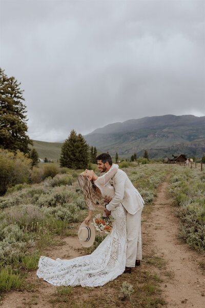 groom dipping bride with mountains in background