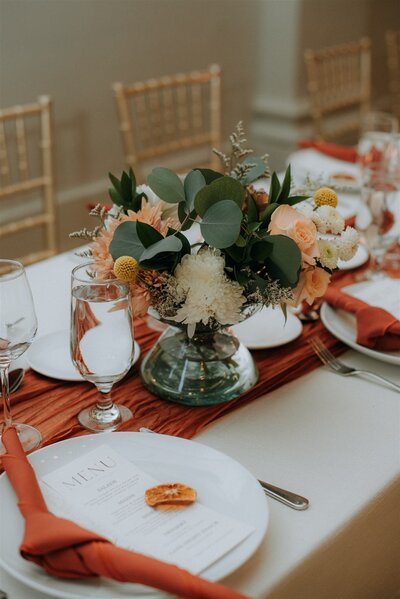 Orange wedding reception tablescape with white florals.