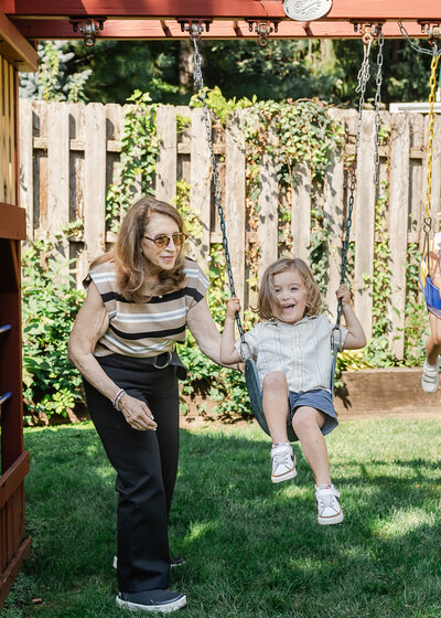 Grandmother pushes grandson on swing in lifestyle photo in a client's home in NI