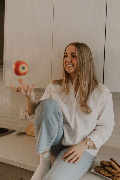 Jenn, an intuitive eating nutritionist, tossing an apple in the air