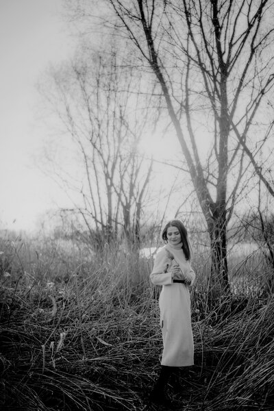 a young woman wearing turtleneck beige dress standing in the field