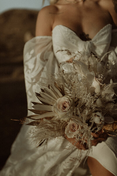 Detail shot of bride wearing her dress and holding her bouquet at her elopement in Joshua Tree National Park