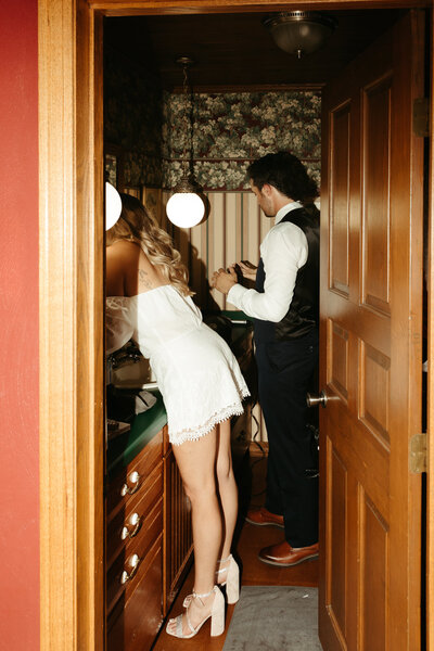 bride and groom get ready for their wedding day together in the bathroom