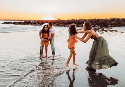 Family of four playing at the beach during sunset