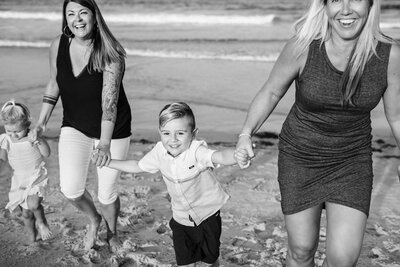 two moms running with children on beach for family photos at the Jersey Shore.