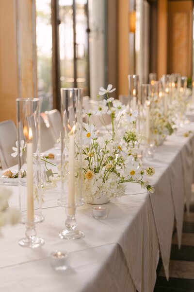 Farewell brunch tablescape with tall taper candles and delicate white florals — elegant post-wedding celebration details