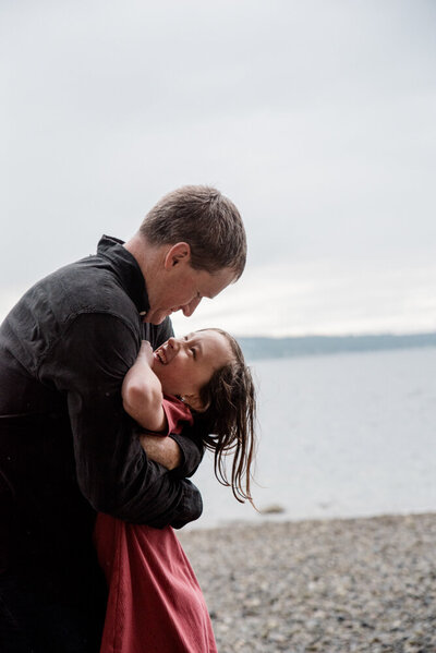 Dad and daughter hugging in the rain at Titlow Beach in Tacoma, WA for family photo session