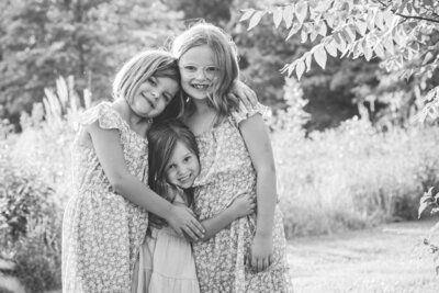 Black and white portrait of three sisters hugging each other and smiling