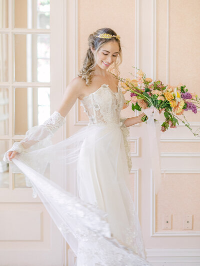 Smiling bride in lace dress holding colorful flowers