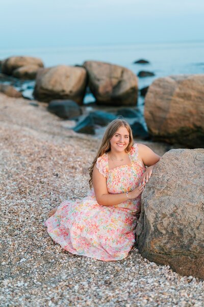 A senior leans against a rock for her senior portrait. 