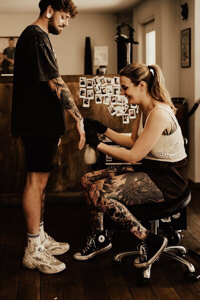 Tatuerare Beccsla på Artcore Tattoo Båstad sätter på stencil på kunds hand.