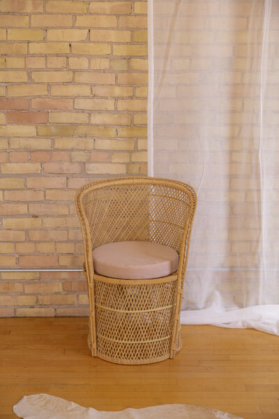 A small rattan chair with a light brown cushion.