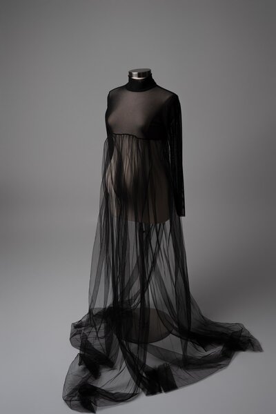 Sheer black gown with layered tulle and long sleeves on mannequin